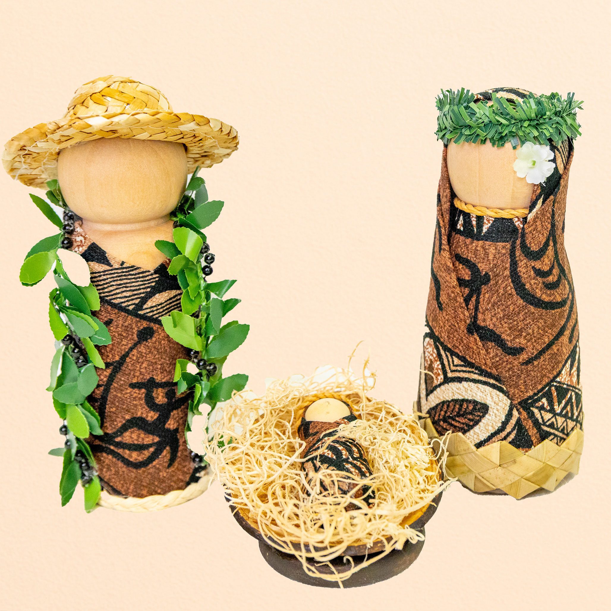 Three wooden nativity figures in traditional island attire with straw, leaves, and floral decorations
