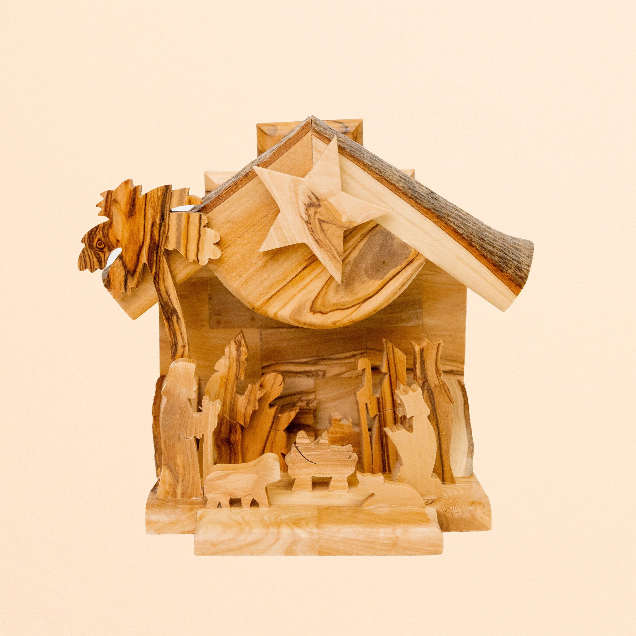Hand-carved wooden nativity scene with stable, star, animals, and figures in natural wood tones