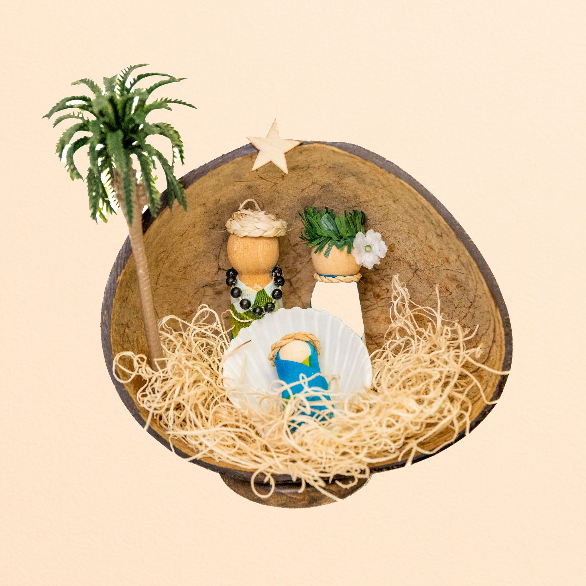 Nativity scene ornament in a coconut shell with palm tree, straw, and seashell figures