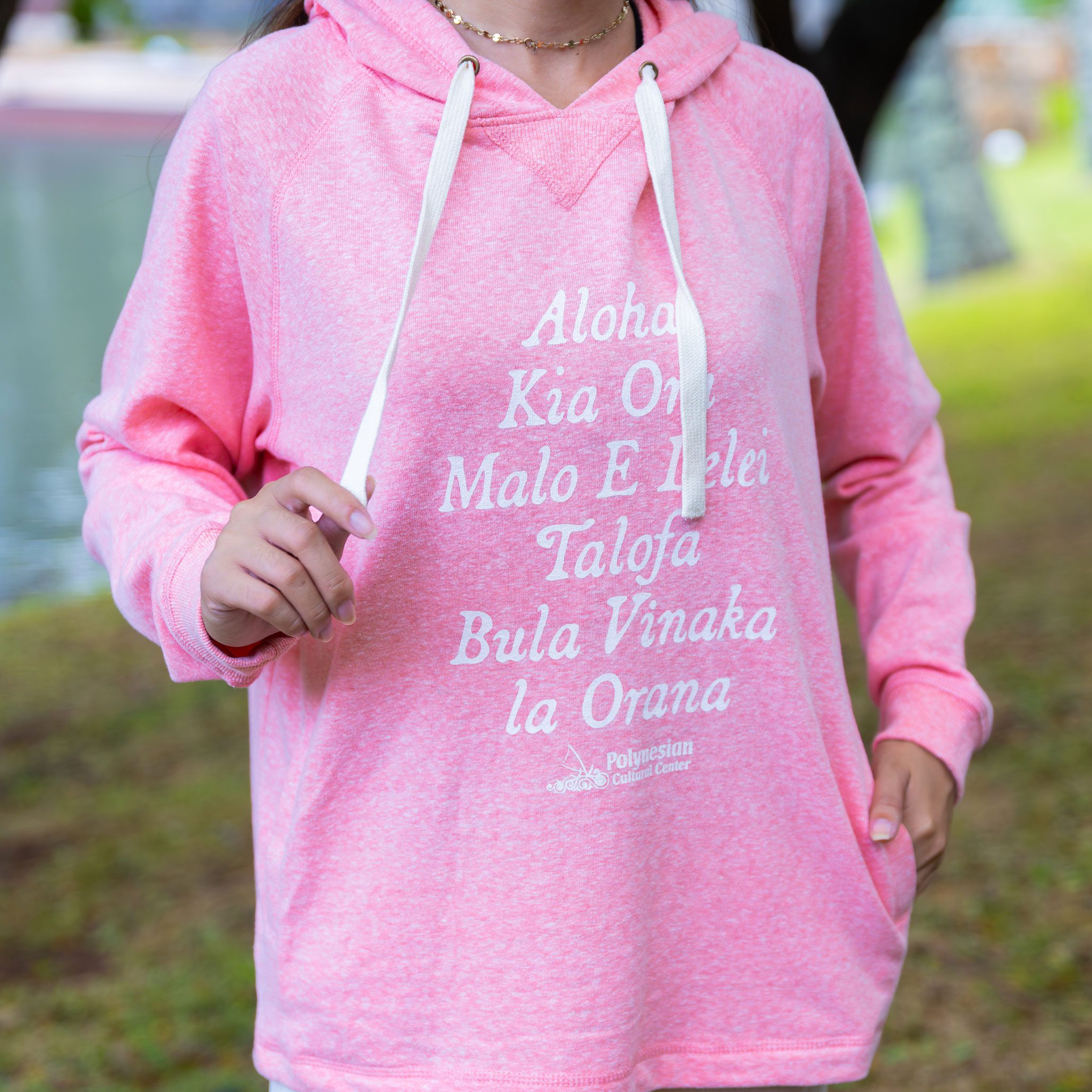 Person wearing a pink hoodie with Polynesian greetings printed on the front.