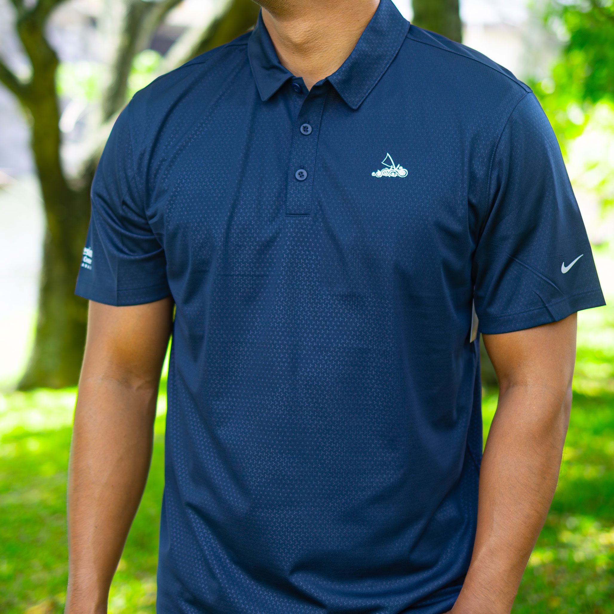 Man wearing a dark blue polo shirt outdoors.